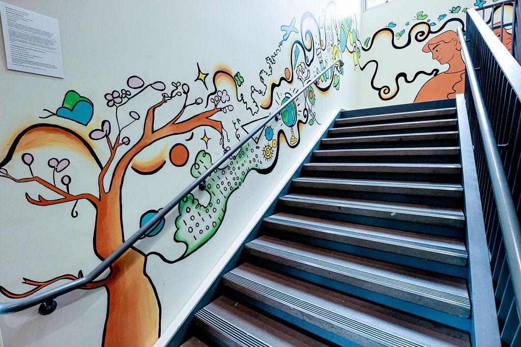 Looking up the bottom flight: the cherry tree, globe and rocket run along the handrail toward the two figures