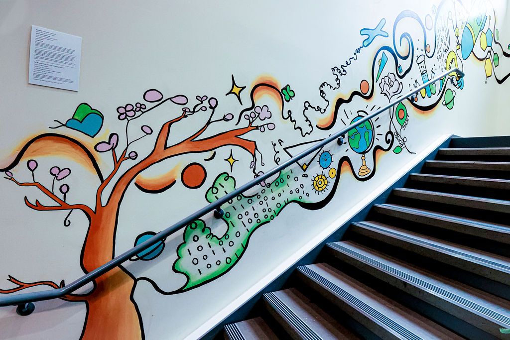 The painted bottom wall along the stairs: the tree, the green binary field and the globe