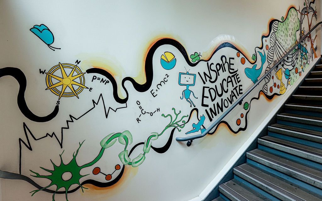 The upper flight: a compass, a neuron and the words Inspire, Educate, Innovate along the stairs